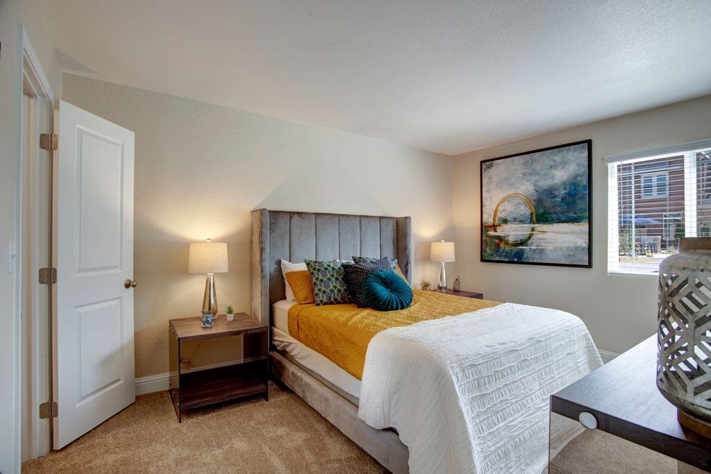 A bedroom with a bed, nightstands, and a painting on the wall.